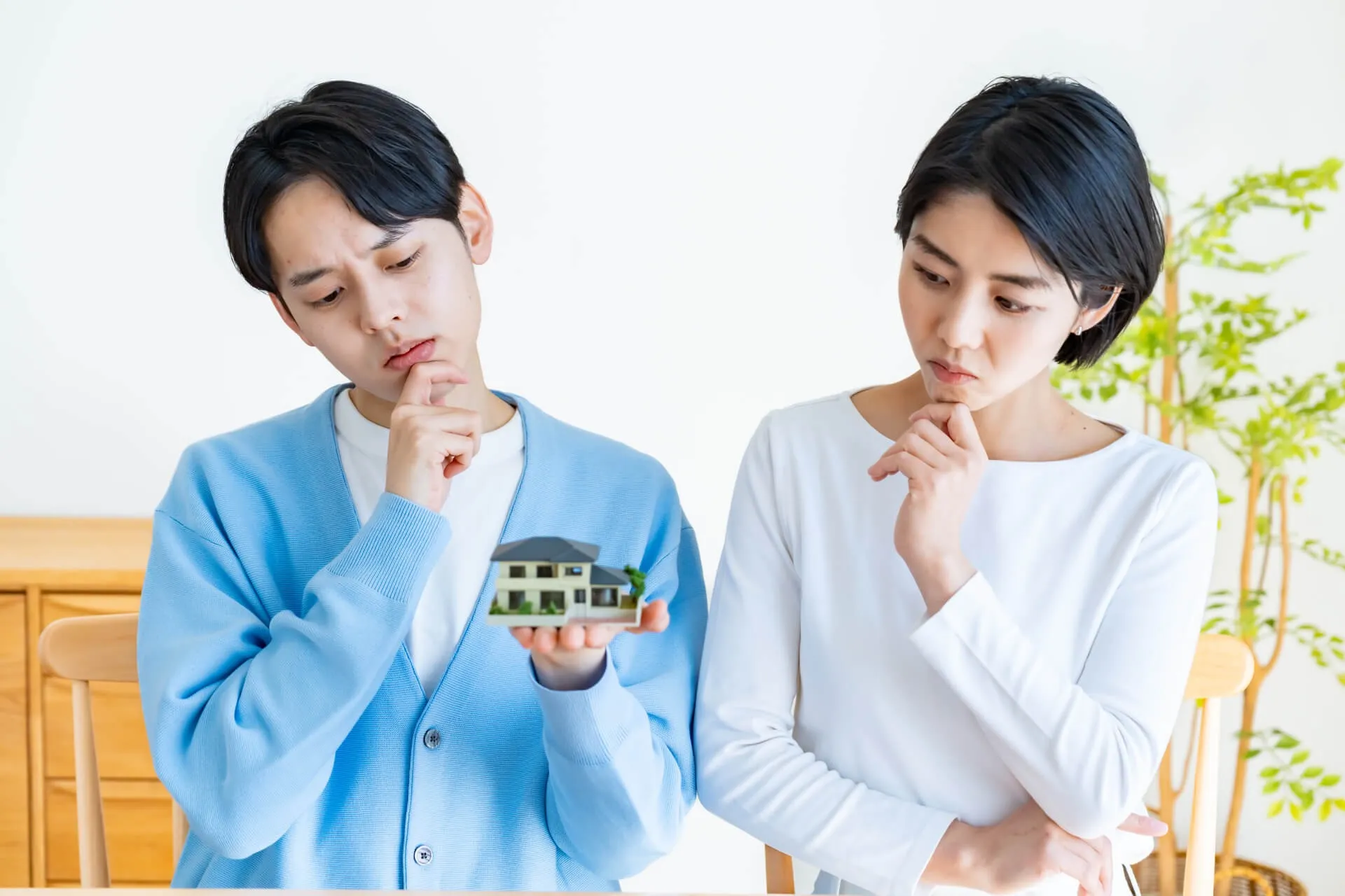 家の模型を見つめる若いカップル